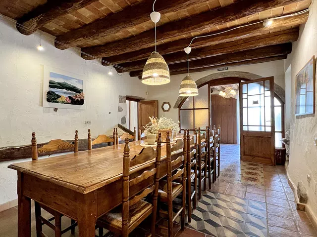 comedor de Can Bayre con mesa larga de madera y bonitas puertas de crista y madera de fondo